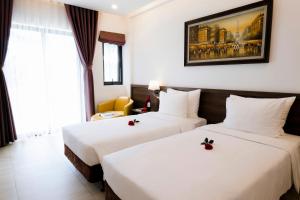 two beds in a hotel room with white sheets at CEREJA Hotel & Resort Dalat in Da Lat