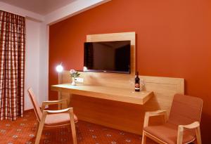 a room with a desk with a television and chairs at Hotel & Restaurant Waldcafe Hettstedt in Hettstedt