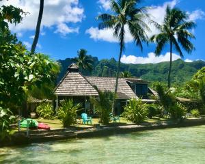 a house on the shore of the water with palm trees at Poerani Moorea in Moorea