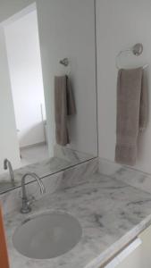 eine Badezimmertheke mit einem Waschbecken und einem Spiegel in der Unterkunft Studio em Cachoeira Paulista in Cachoeira Paulista