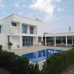 a white house with a swimming pool in front of it at Casa Quinta Flower in Melgar