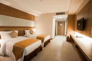 a hotel room with two beds and a flat screen tv at Garden Sentral Hotel in Kuala Belait