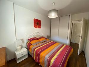 1 dormitorio con 1 cama con una manta a rayas de colores en Appartement Capbreton, 2 pièces, 4 personnes - FR-1-413-208 en Capbreton