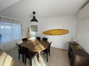 une salle à manger avec une table et une planche de surf sur le mur dans l'établissement Villa Capbreton, 6 pièces, 13 personnes - FR-1-413-209, à Capbreton