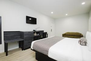 a bedroom with a bed and a desk and a television at Sapphire Inn & Suites in Deer Park