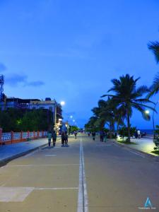 a group of people walking down a street with palm trees at Villa Felicia 1Bbk property in Pondicherry
