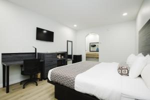 a bedroom with a bed and a desk and a television at Sapphire Inn & Suites in Deer Park