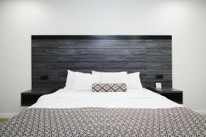 a bedroom with a white bed with a black headboard at Sapphire Inn & Suites in Deer Park