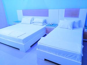2 bedden in een hotelkamer met witte lakens bij Hotel Royal Star in Multan