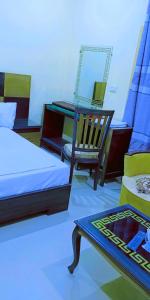 een kamer met 2 bedden, een stoel en een spiegel bij Hotel Royal Star in Multan