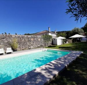 una piscina frente a una pared de piedra en 3 bedrooms house with shared pool enclosed garden and wifi at Covelas Povoa de Lanhoso en Póvoa de Lanhoso