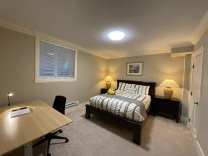 a bedroom with a bed and a desk and a table at New two-bedroom legal suite with parking in White Rock