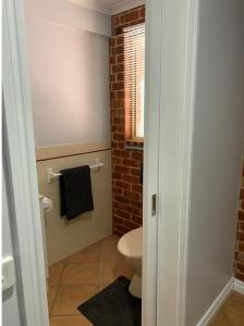 a bathroom with a toilet and a brick wall at Jeryn On Jephcott in Corryong