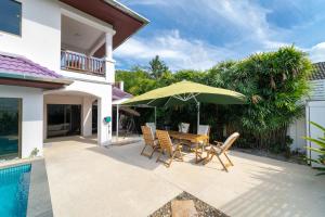 a patio with a table and chairs and an umbrella at Villa Amaya, 2 Story Tropical Oasis with Green Hills View & Pool, Kamala Beach in Kamala Beach