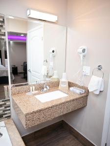 La salle de bains est pourvue d'un lavabo et d'un grand miroir. dans l'établissement Diamond Bell Inn & Suites, à Bell