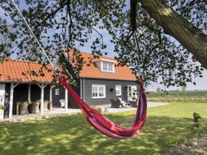 a red hammock hanging from a tree in front of a house at Rustic Holiday Home In Wissenkerke With Garden in Wissenkerke