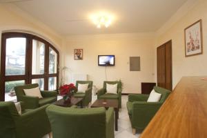 a living room with green chairs and a table at Hotel The Marquee in Castelnuovo di Garfagnana