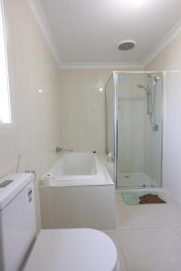 a white bathroom with a shower and a toilet at Melbourne Lovely Nest in Melbourne