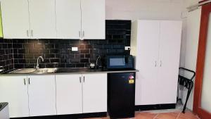 a kitchen with white cabinets and a microwave at Gosford Inn Motel in Gosford