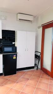 a kitchen with white cabinets and a black refrigerator at Gosford Inn Motel in Gosford