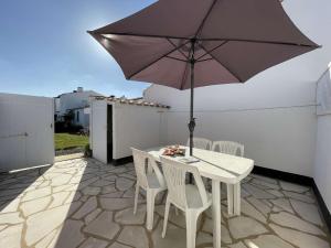 - une table et des chaises avec un parasol sur la terrasse dans l'établissement Maison Bretignolles-sur-Mer, 2 pièces, 4 personnes - FR-1-224A-12, à Bretignolles-sur-Mer