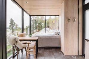 The WonderInn Mirrored Glass Cabin - Wonderinn Delta في Hektner: غرفة نوم بسرير وطاولة وكراسي
