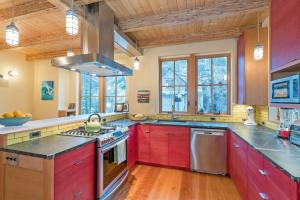 a large kitchen with red cabinets and windows at Sun-Filled Sunnyside Home On North Fir St - Eco-Friendly Home - Peace & Privacy home in Telluride