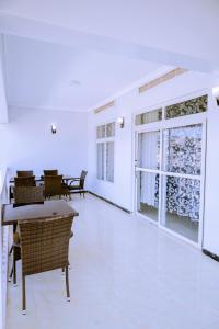 Habitación blanca con mesas, sillas y ventanas en Lao Tangren Guest House, en Kigali