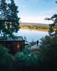 a man standing on a path next to a lake at The WonderInn Mirrored Glass Cabin - Wonderinn Delta in Hektner