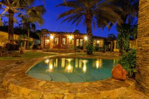 ParaguachiVilla Cococaribic Isla Margarita Venezuela的棕榈树环绕的房子前的游泳池