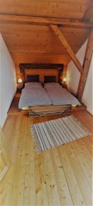 a bed in a wooden attic with a wooden floor at Podkrovie v zeleni - privat in Štrba
