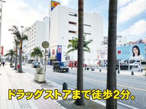 a city street with palm trees and a building at 琉球カプセルホテル8131那覇国際通り in Naha