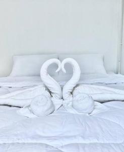 two white swans making a heart on a bed at p.p. hill & house in Ban Tha Phae