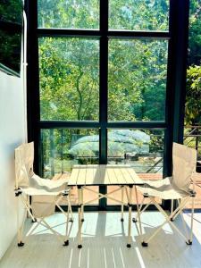 a table and two chairs in front of a window at p.p. hill & house in Ban Tha Phae