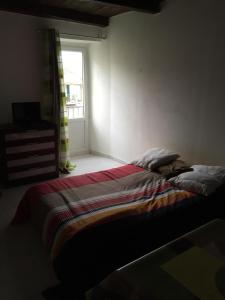 a bedroom with a bed with a striped blanket and a window at Studio Haute Ville in Corte