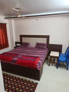 um quarto com uma cama e uma cadeira azul em Sri vishnu krupa lodging em Belūr
