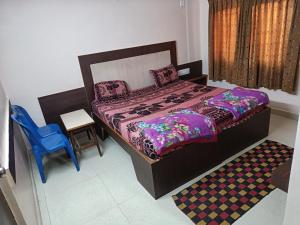 a bedroom with a bed and a blue chair at Sri vishnu krupa lodging in Belūr