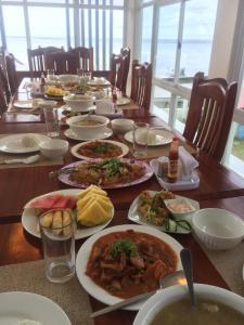 a long wooden table with plates of food on it at Elnora Delmar Travellers Inn in Siquijor