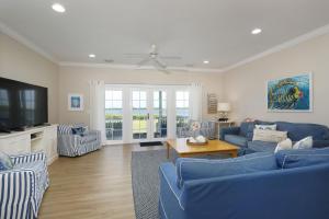 un salon avec des canapés bleus et une télévision dans l'établissement Waterfront luxury Villa 54 with sunset views and boat slip townhouse, à Marathon