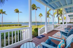une terrasse couverte avec des chaises, des palmiers et l'océan dans l'établissement Waterfront luxury Villa 54 with sunset views and boat slip townhouse, à Marathon