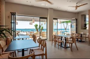 un restaurante con mesas y sillas y vistas a la playa en Frini Hotel en La Canea