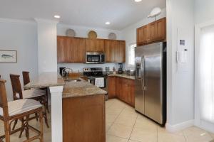 a kitchen with wooden cabinets and a stainless steel refrigerator at Waterfront luxury Villa 34 with sunset views and boat slip townhouse in Marathon