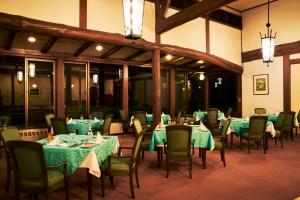 a dining room with tables and chairs with green table cloth at Tsumagoi Prince Hotel in Tsumagoi