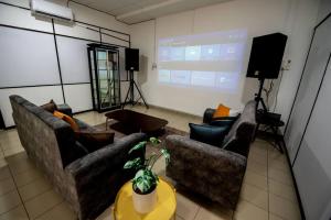 a living room with two couches and a projection screen at De Luma (The Rumah)@3bedroom (Sunflower) in Bukit Mertajam