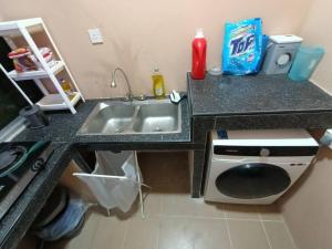 a kitchen counter with a sink and a washing machine at HS Homestay in Sandakan