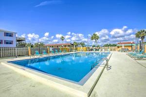 a large swimming pool with blue chairs around it at Sunny St Augustine Condo with Community Pool! in St. Augustine