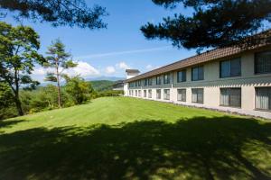 a building with a large grass field in front of it at Tsumagoi Prince Hotel in Tsumagoi