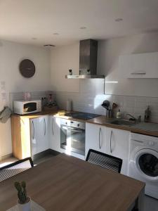 a kitchen with white appliances and a table in it at La maison d’à côté in Troyes +10 photos