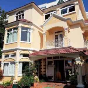a large yellow house with a porch on a street at Euro Vacances Guest House in Roches Brunes