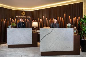 two people standing behind reception desks in a lobby at Soleil Boutique Hotel Hanoi in Hanoi